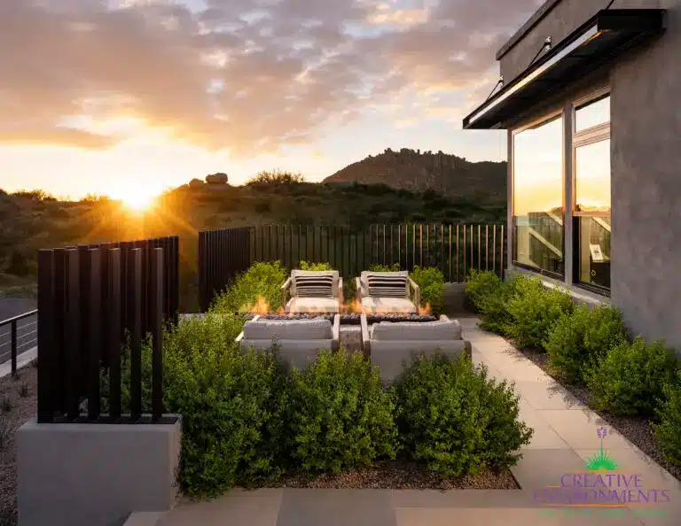 Custom backyard design with metal fencing, fire table and outdoor seating area.