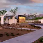 Custom community entryway with custom entryway sign, white shade structure and organized planting.