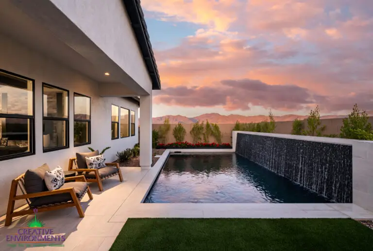 Custom backyard design with black water wall into pool, organized planting and natural stone decking.