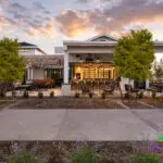 Custom community entrance with string lights, white shade structure and multiple seating areas.