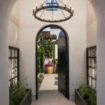 Unique front entry way with chandelier, metal trellis and arched door/doorway.
