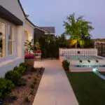 Custom backyard design with natural stone walkway, organized planting and a deco-tile spa that feeds into a metal scupper water feature.