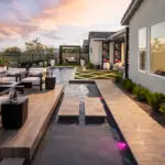 Custom backyard design with Jesus steps, unique shaped pool and raised seating area with floating fire table.