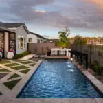 Custom backyard design with artificial turf pattern, water scuppers into pool with natural stone decking.