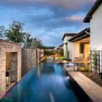 Custom backyard design with metal trellis and unique shaped, zero-edge pool.