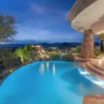Backyard design with curved pool and up lighting.
