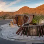 Custom community entrance with metal statement piece, roundabout driveway and multiple seating areas.