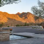 Custom community entrance with water feature, roundabout driveway and unique metal shade structure.