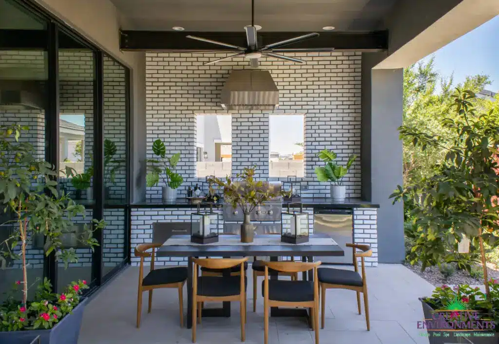 Custom backyard design with outdoor kitchen, outdoor seating areas and large planters.