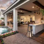 Custom backyard design with wooden ceiling beams, water feature and organized planting.