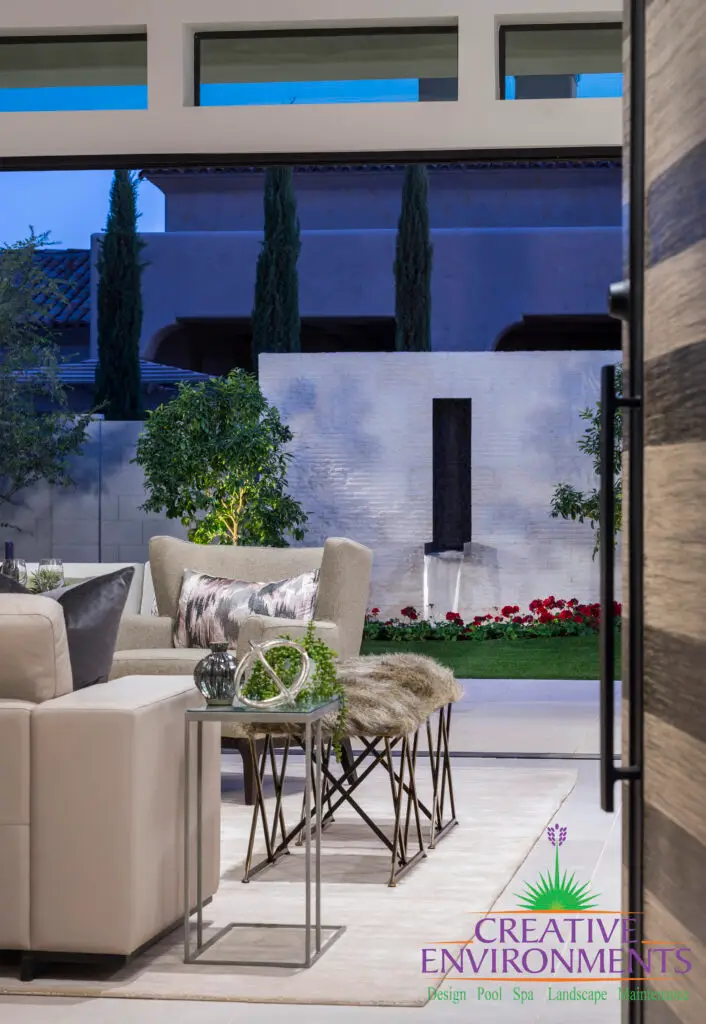 Custom backyard design with metal scupper water feature, up lighting and outdoor seating area.