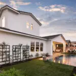 Custom backyard design with metal trellis, zero-edge pool and multiple seating areas.