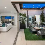 Custom indoor/outdoor fusion with outdoor dining area, string lights and large metal planters.