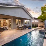 Custom backyard design with blue pool, metal scupper water feature and outdoor bar.