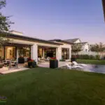 Custom backyard design with artificial turf, metal shade structure with rain curtain water feature and large metal planters.