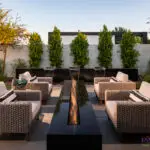 Custom backyard design with metal scupper water feature, fire pit and privacy hedges.