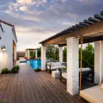 Custom backyard design with slatted shade structures, hanging daybed and blue pool.