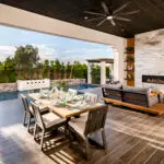 Custom backyard design with floor-to-ceiling marble fireplace, privacy hedges and multiple seating areas.