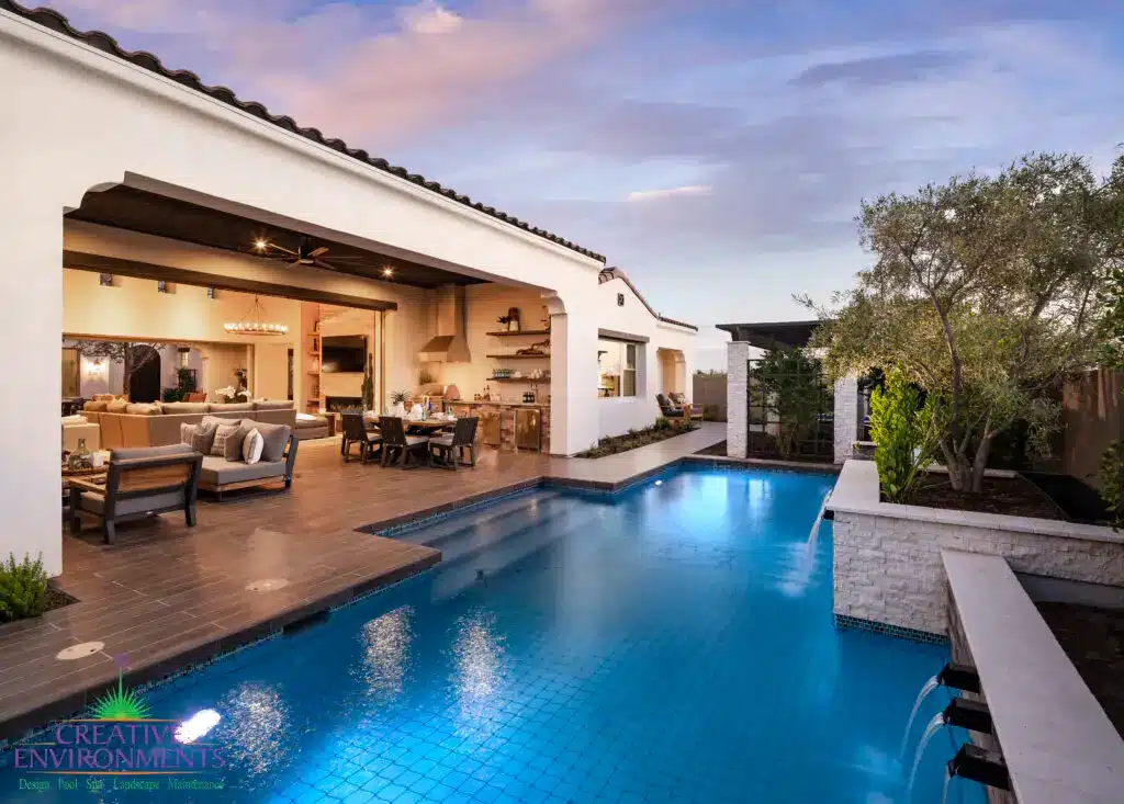 Custom backyard design with natural stone accents, blue pool and privacy hedges.
