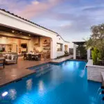 Custom backyard design with natural stone accents, blue pool and privacy hedges.