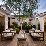 Custom entryway courtyard with large tree, multiple large metal planters and floating fire table.