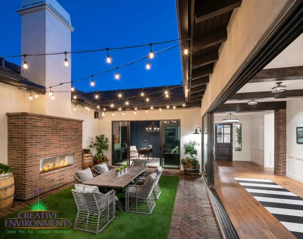Custom backyard design with string lights, fireplace and outdoor dining area.