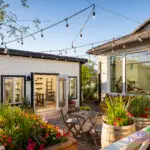 Custom backyard design with gardening area, string lighting and multiple planters.