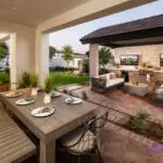 Custom backyard design with multiple outdoor seating areas, artificial turf and organized planting.