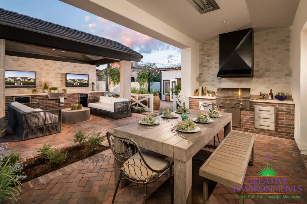 Custom backyard design with outdoor BBQ, multiple seating areas and string lighting.