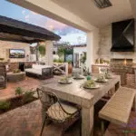 Custom backyard design with outdoor BBQ, multiple seating areas and string lighting.