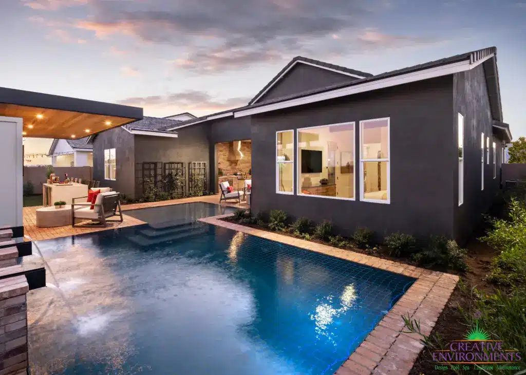 Custom backyard design with blue pool, cantilevered shade structure and metal trellis.
