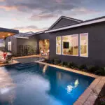 Custom backyard design with blue pool, cantilevered shade structure and metal trellis.