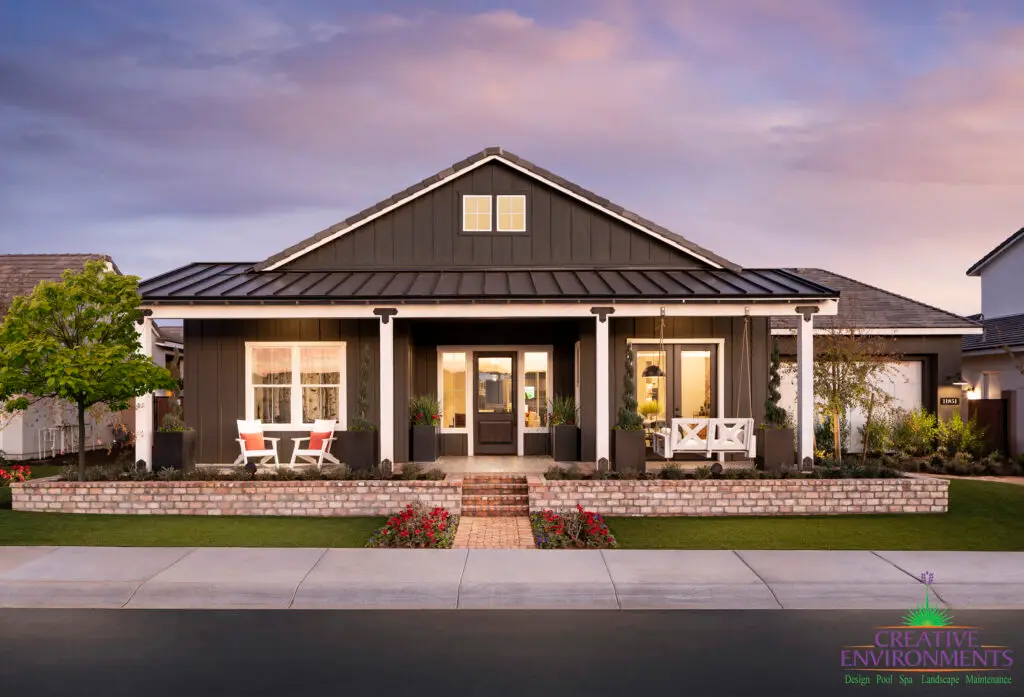 Custom front yard design with brick privacy wall, annuals and multiple seating areas including a hanging front porch swing.