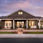 Custom front yard design with brick privacy wall, annuals and multiple seating areas including a hanging front porch swing.