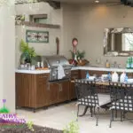 Custom backyard design with outdoor kitchen, outdoor dining area and planters.