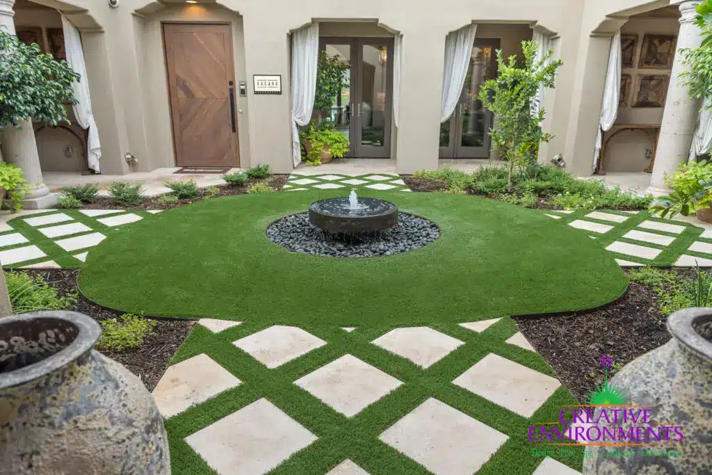 Custom courtyard design with artificial turf pattern, water feature and organized planting.