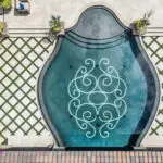 Custom backyard design with unique-shaped pool, artificial turf pattern and multiple seating areas.