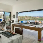 Custom indoor/outdoor design fusion with outdoor entertainment area, pool table and multiple seating areas.