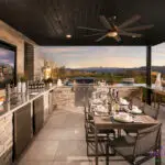 Custom backyard design with outdoor kitchen, multiple seating areas and metal fencing.