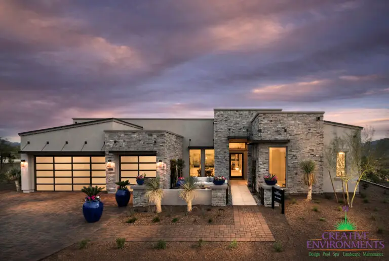 Custom front yard design with metal accents, up lighting and brick paver walkway and driveway.