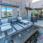 Backyard design with multiple seating areas and metal planters.