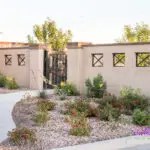 Custom community entrance with metal cutouts, metal gate door and organized planting.
