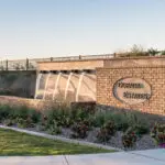 Custom community entrance with entryway sign, metal scupper water feature and organized planting.