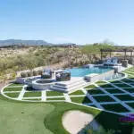 Custom backyard design with multiple seating areas, artificial turf pattern and putting green.