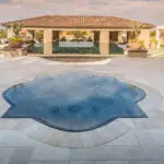 Custom backyard design with unique-shaped spa, large planters and multiple seating areas.