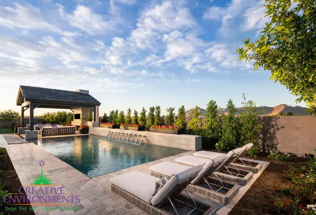 Custom backyard design with privacy hedges, metal scupper water feature into pool and multiple seating areas.