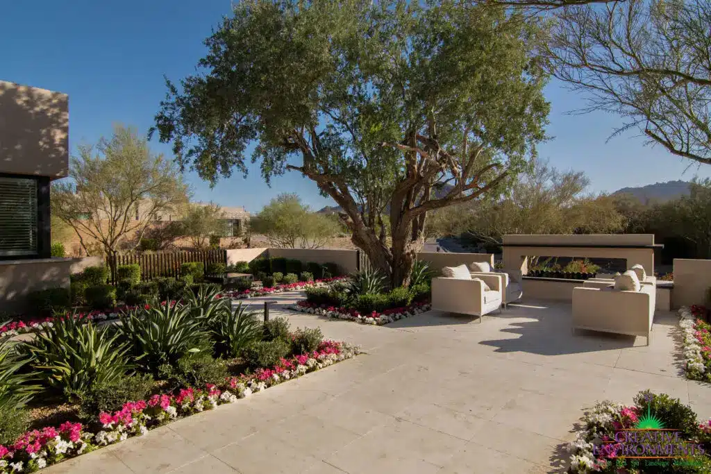Custom backyard design with fireplace, organized planting and tree.