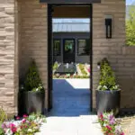 Custom backyard design with entryway door, annuals and large planters.