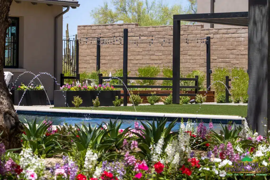 Custom backyard design with string lights, large planters and water feature into pool.