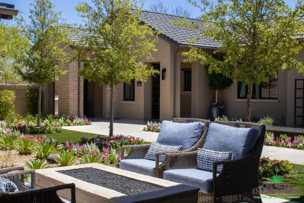 Custom front yard design with trees, fire table and organized planting.
